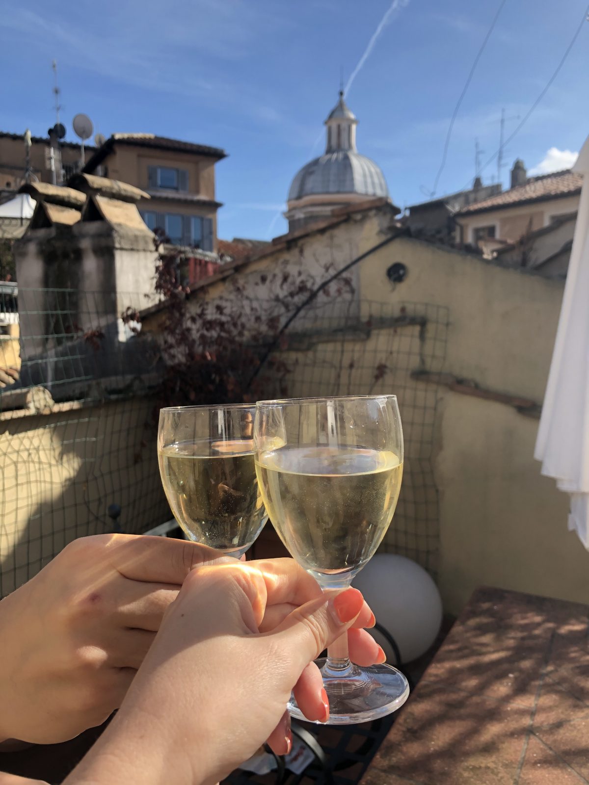 Anstoßen auf unsere Unterkunft mit großer Dachterrasse direkt am Campo de Fiori Wein genießen auf einer Dachterrasse in Rom, Italien