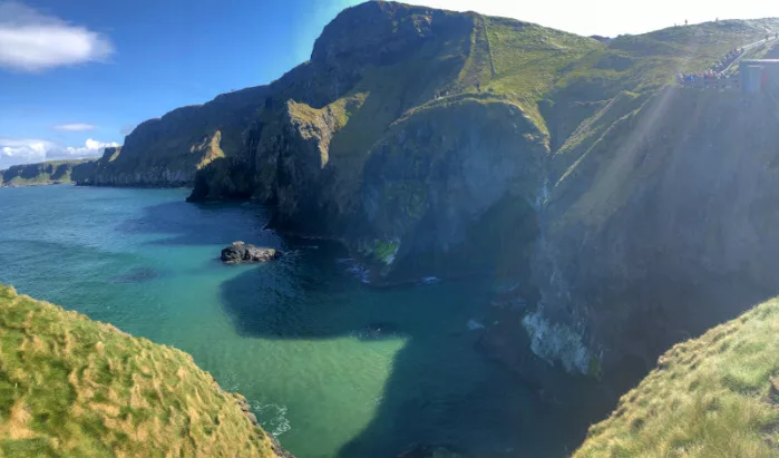 Dank Sonne leuchtet der Atlantik türkis und die Felsen werfen riesige Schatten auf das Meer Irland Roadtrip: Aussicht von Carrick-A-Rede auf die Klippen