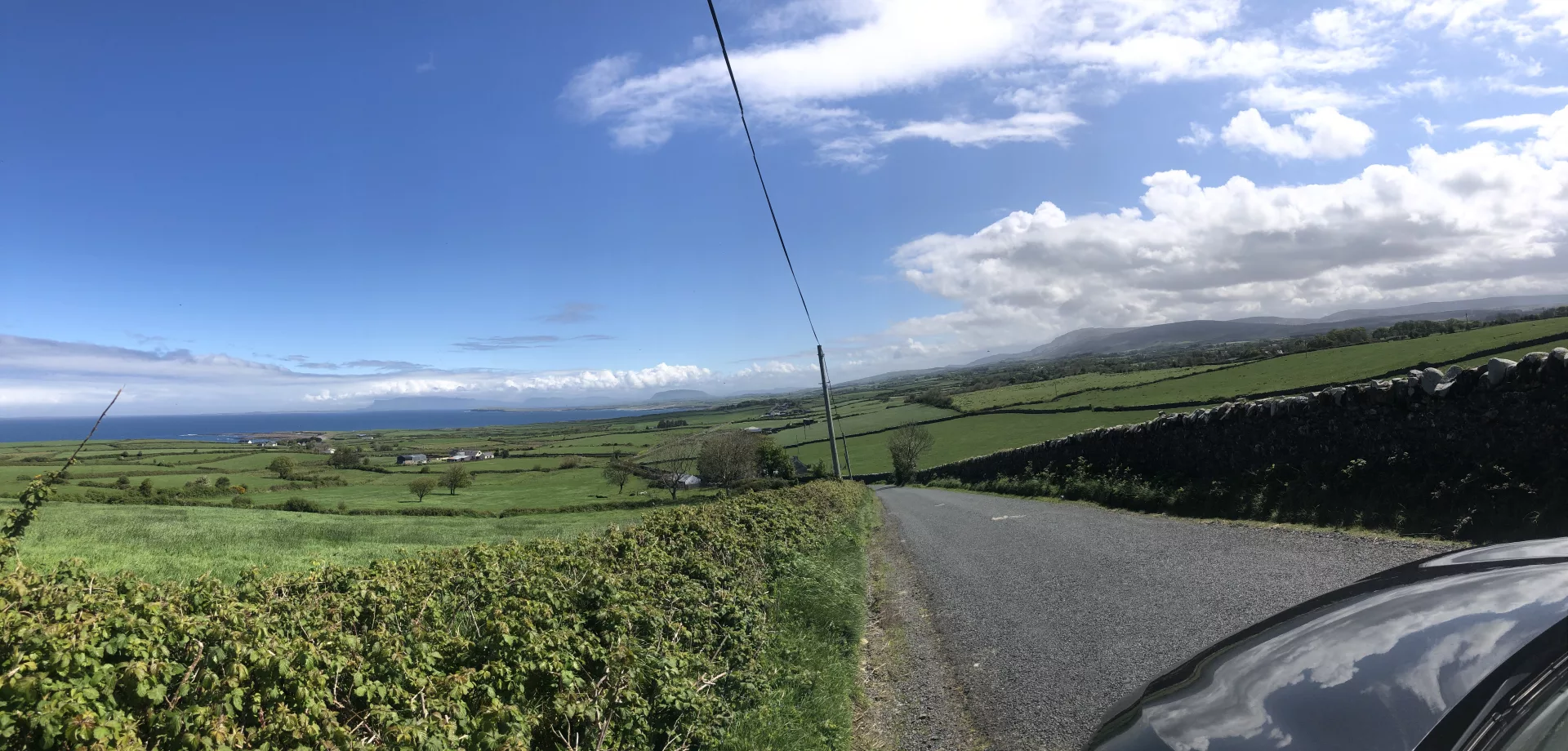 Irland Roadtrip durch die grüne Landschaft mit Atlantikküste im Hintergrund