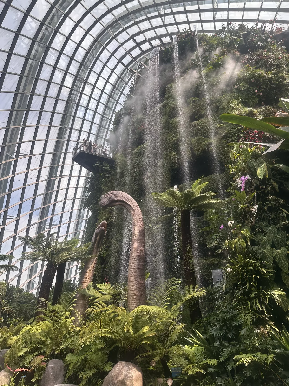 Am Wasserfall stehen während der Jurassic World Experience riesige Saurier Am Wasserfall des Cloud Forest stehen während der Jurassic World Experience riesige Saurier