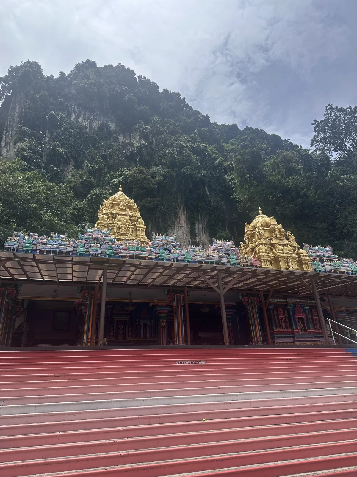 Die Tempelanlagen bilden einen leuchtenden Kontrast zu den beeindruckenden Felsen Tempel vor den Felsen an den Batu Caves