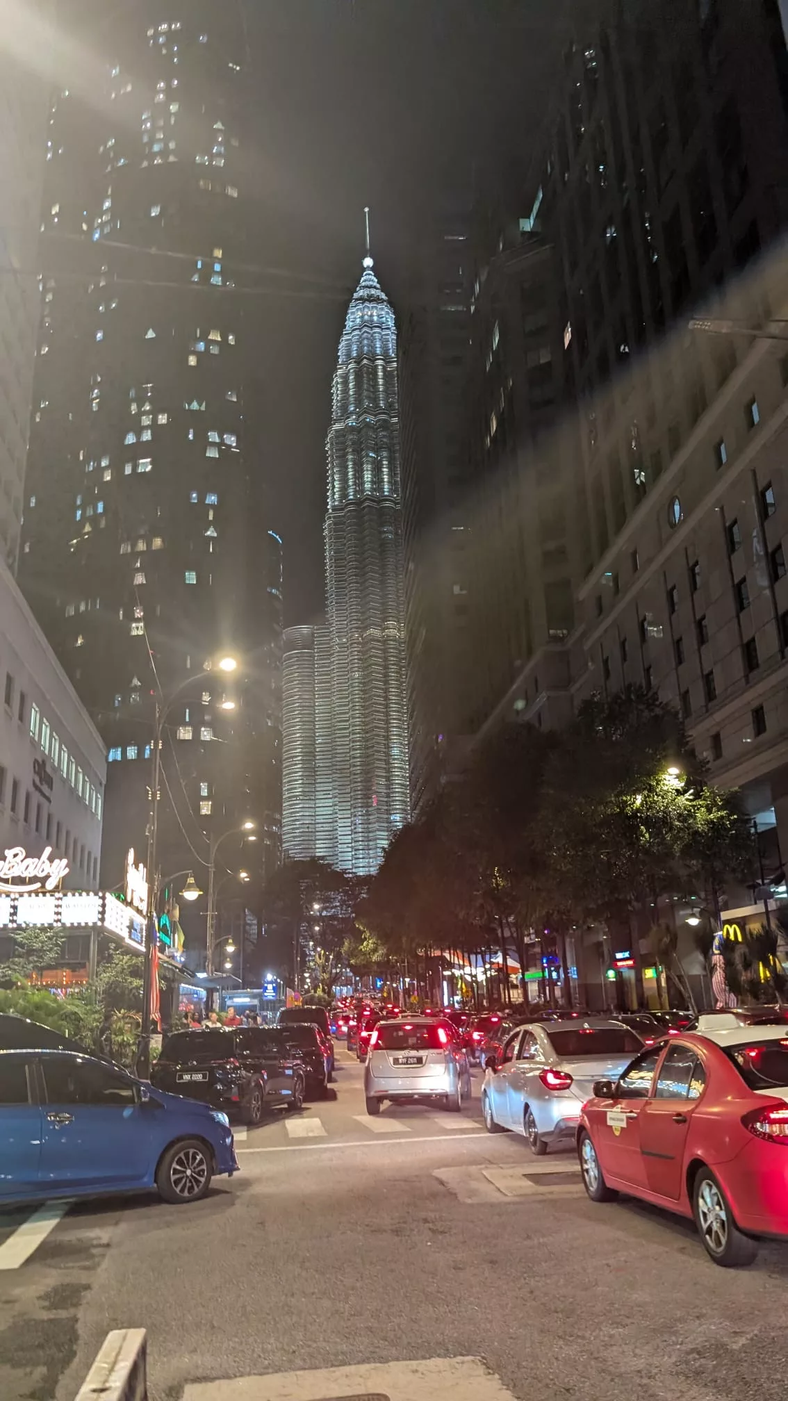 Die 3 Riesen von Kuala Lumpur: die Petronas Towers (452 Meter hoch)… Am Abend viel befahrene Straße im Zentrum von Kuala Lumpur mit Petronas Towers im Hintergrund