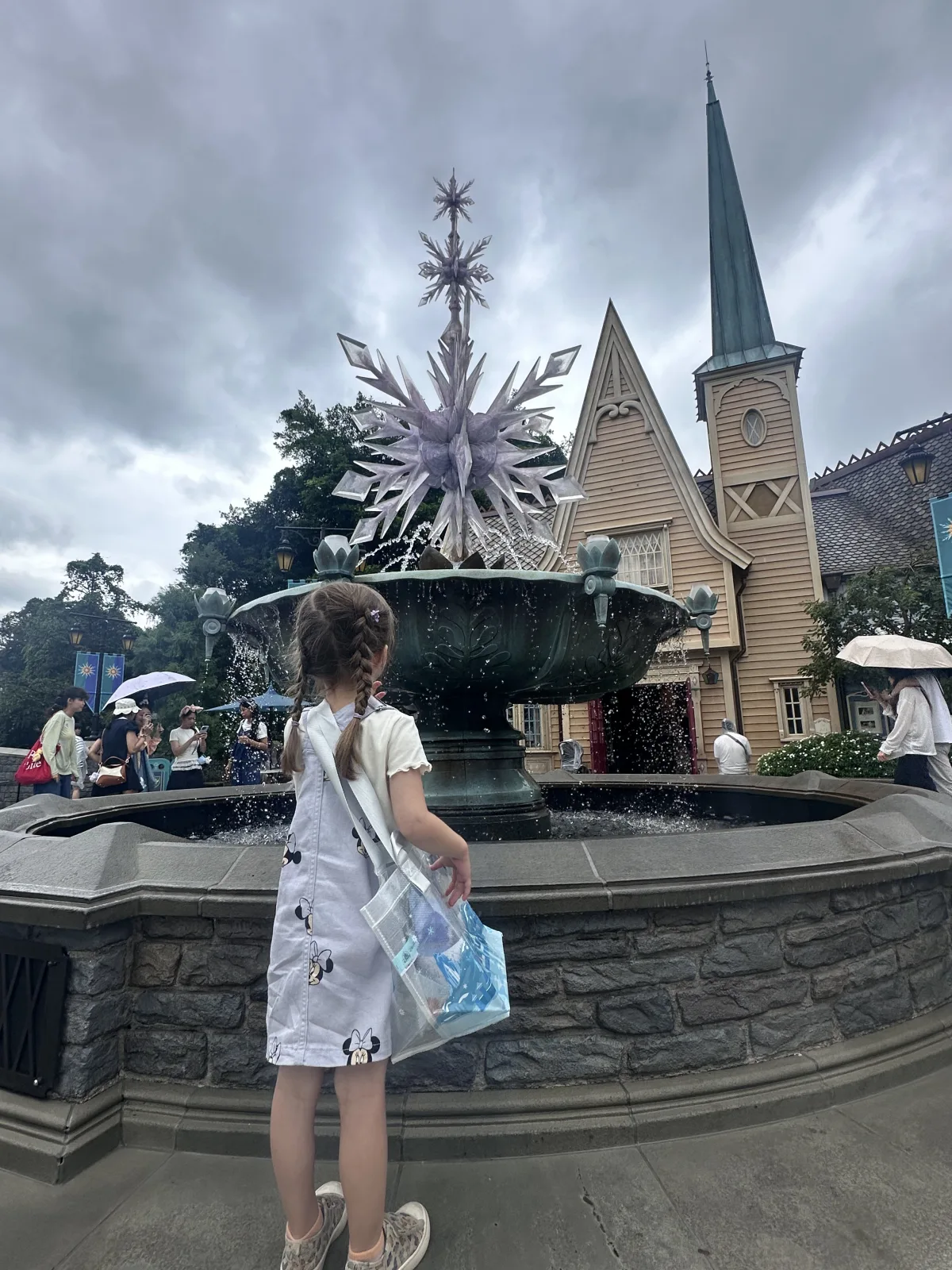 Kleiner Frozen-Fan vor dem Springbrunnen mit Eiskristallen Springbrunnen mit Eiskristallen in der World of Frozen im Disneyland Hongkong