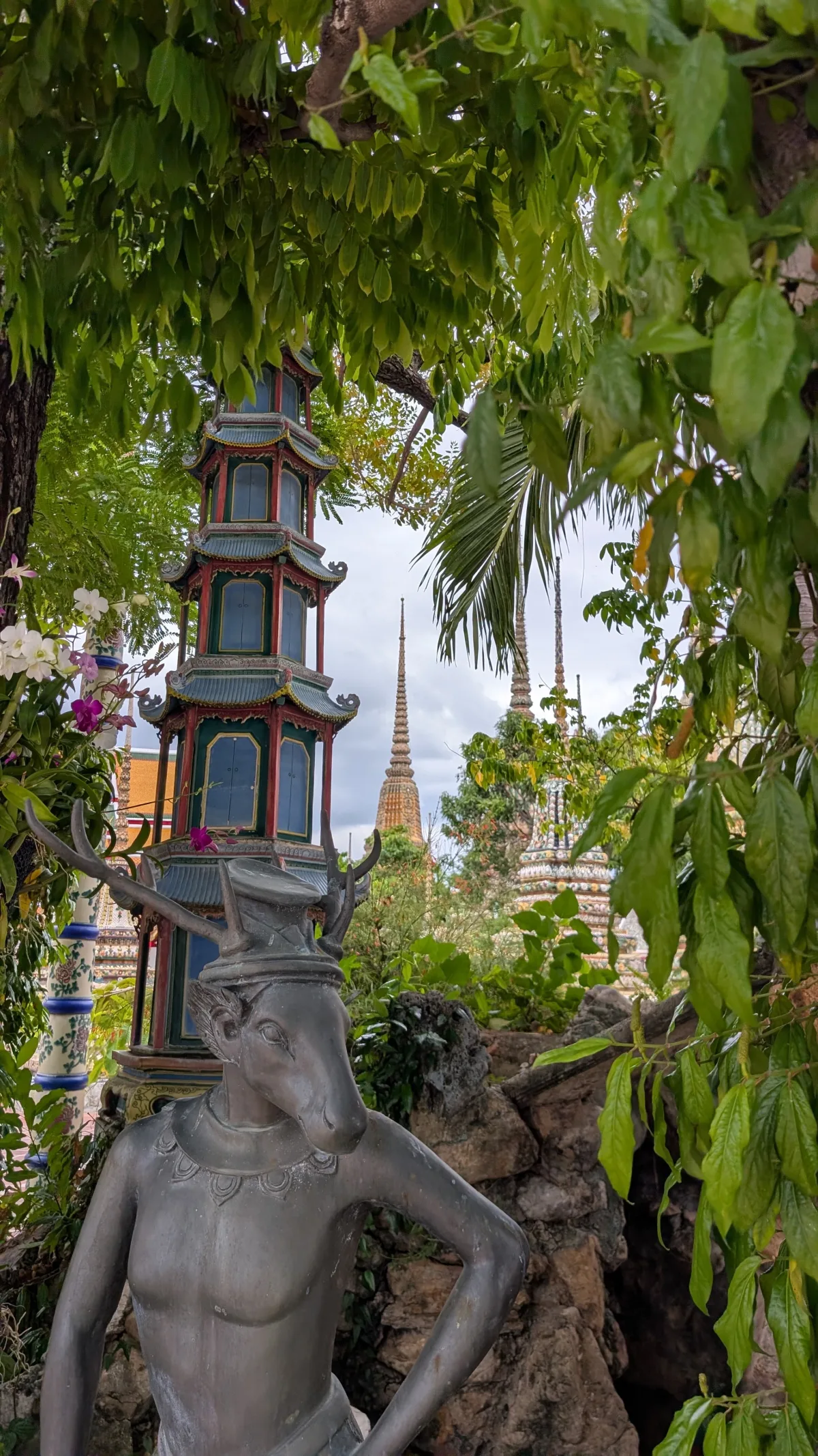 In den grünen Außenanlagen finden sich überall Statuen, nicht nur von Buddha Grüne Außenanlagen mit Statuen am Tempel Wat Pho in Bangkok