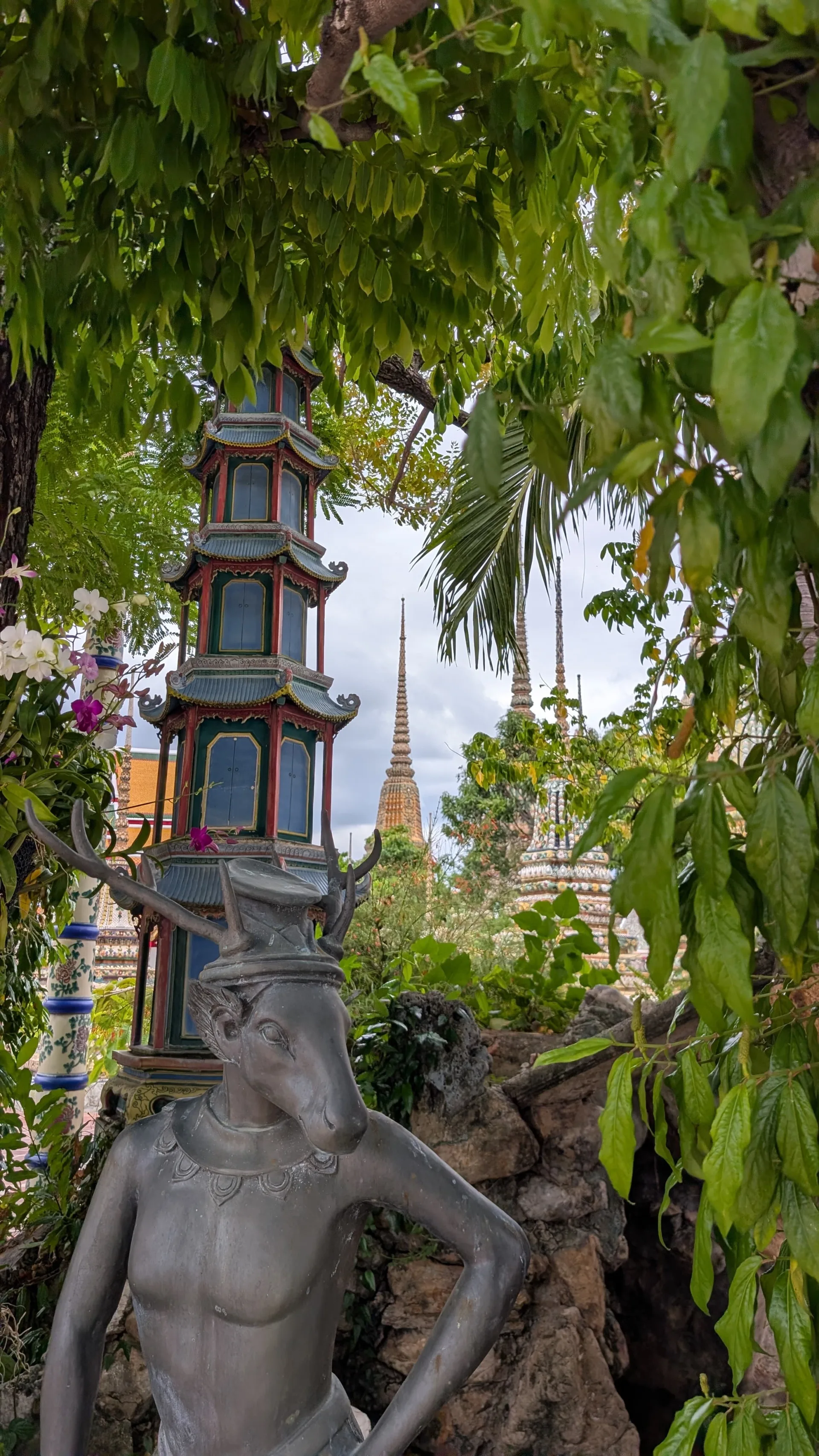 Grüne Außenanlagen mit Statuen am Tempel Wat Pho in Bangkok